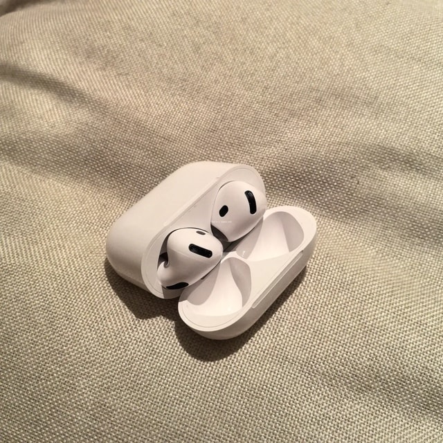 AirPods 4 open charging case on a woven surface